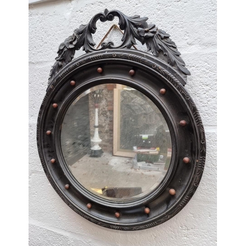 1090 - An antique ebonized circular wall mirror, 59cm diameter. 