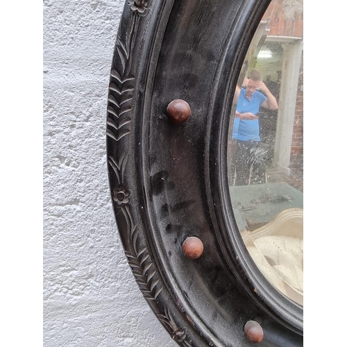 1090 - An antique ebonized circular wall mirror, 59cm diameter. 