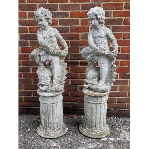 1121 - A pair of old painted and weathered composition stone cherub and dolphin figures, on pedestals, 128c... 