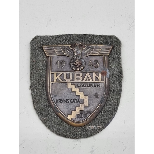 1495 - A German Third Reich Wehrmacht Kuban shield badge, 6cm high, on grey cloth panel.