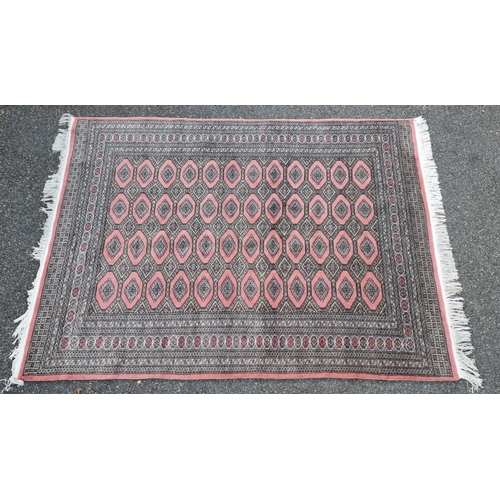 1130 - A large Bokhara rug, having repeated decoration to central field, on a pink ground, 255 x 190cm.... 