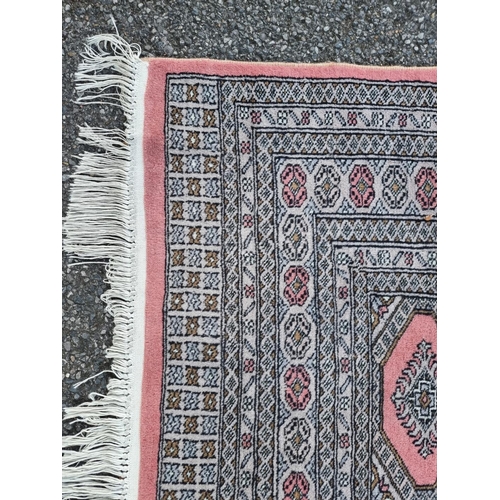 1130 - A large Bokhara rug, having repeated decoration to central field, on a pink ground, 255 x 190cm.... 