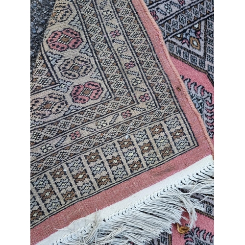 1130 - A large Bokhara rug, having repeated decoration to central field, on a pink ground, 255 x 190cm.... 