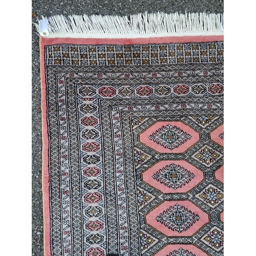 1130 - A large Bokhara rug, having repeated decoration to central field, on a pink ground, 255 x 190cm.... 