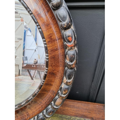 1091 - A 1920s mahogany and ebonized oval wall mirror, 62 x 87cm. 