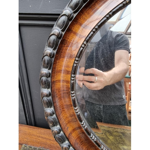 1091 - A 1920s mahogany and ebonized oval wall mirror, 62 x 87cm. 