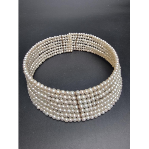 606 - A freshwater pearl seven strand semi rigid choker, having five yellow metal spacers, stamped '14k'.... 