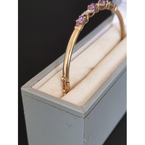 461 - An amethyst and diamond hinged bangle, stamped '9k'.