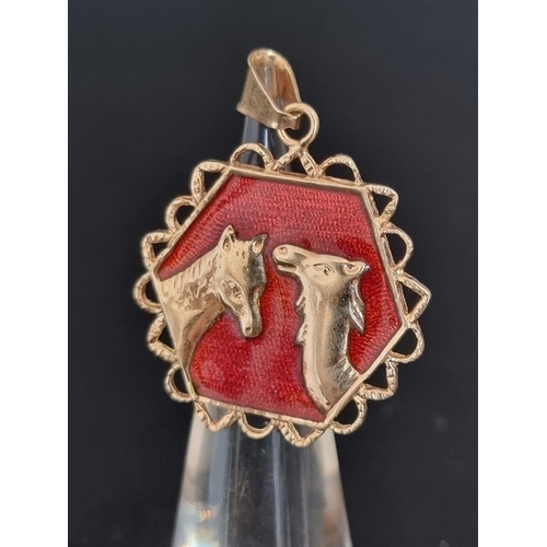 487 - An Iranian yellow metal and red enamel pendant, decorated in relief with a horse and a camel head, t... 