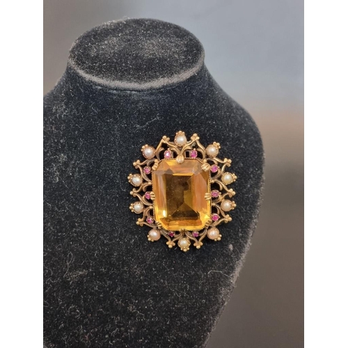 503 - A Victorian yellow metal oval brooch, set rectangular facetted citrine surrounded by ten rubies and ... 