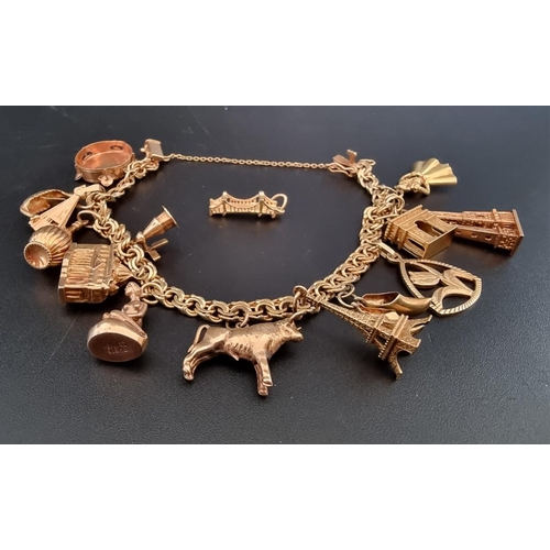 536 - A yellow metal charm bracelet, with fifteen attached charms.