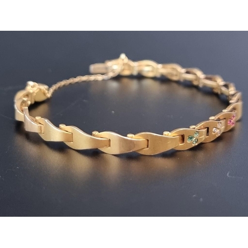 550 - A yellow metal hinged bracelet, set nine small diamonds, rubies and emeralds.