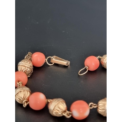 560 - A vintage yellow metal bracelet, set seven interspersed round coral beads, 21cm.