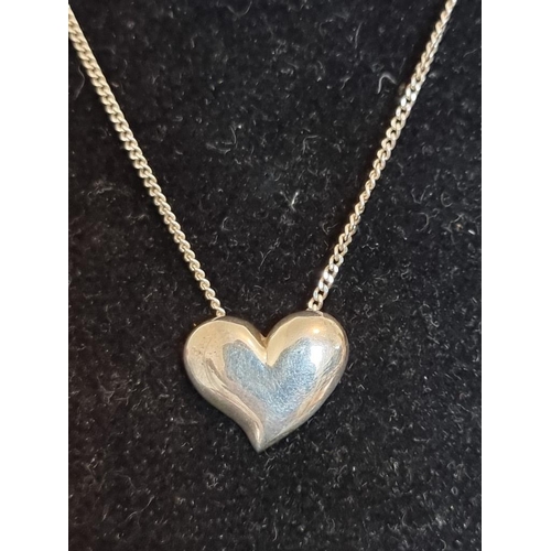 572 - A silver heart pendant, on a white metal necklace chain stamped '935'.