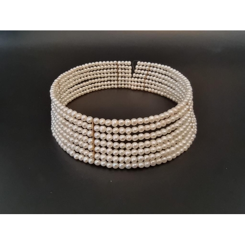 606 - A freshwater pearl seven strand semi rigid choker, having five yellow metal spacers, stamped '14k'.... 