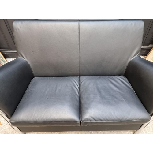 1073 - A pair of contemporary black leather and chrome sofas, by Giulio Marelli, each 123cm wide. ... 