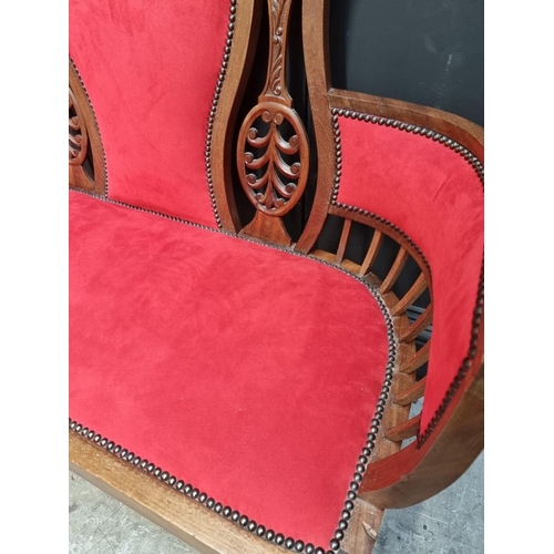 1085 - A circa 1900 carved mahogany and brass studded red suede settee, 124cm wide.