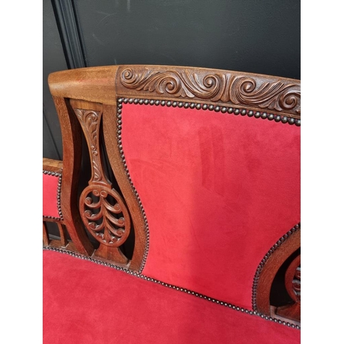 1085 - A circa 1900 carved mahogany and brass studded red suede settee, 124cm wide.