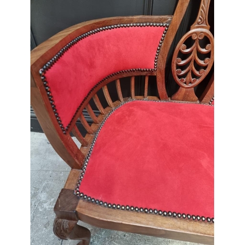 1085 - A circa 1900 carved mahogany and brass studded red suede settee, 124cm wide.