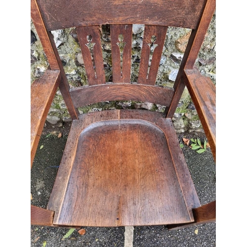 1124 - An unusual Arts & Crafts oak elbow chair, (split to seat).