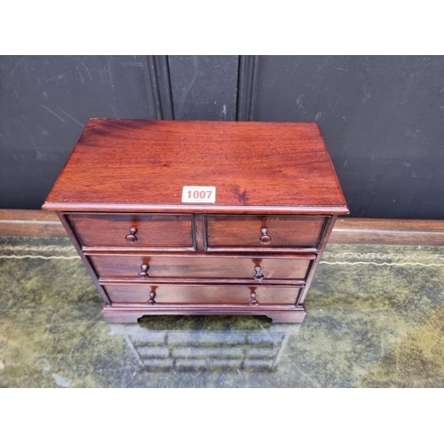 1007 - A miniature hardwood chest of drawers, 24cm high x 28.5cm wide x 15cm deep. 