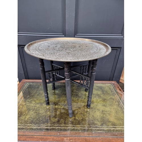 1061 - A brass circular table, on ebonized folding stand, 59cm diameter. 