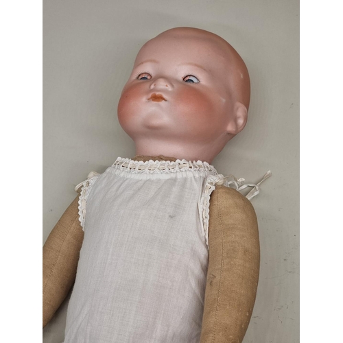 74 - Dolls: an Armand Marseille bisque head baby doll, with blue sleeping eyes and cloth body, (losses to... 