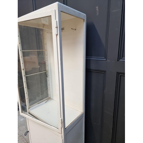 1002 - A vintage white painted metal chemist's display cabinet, 170.5 high x 60cm wide.