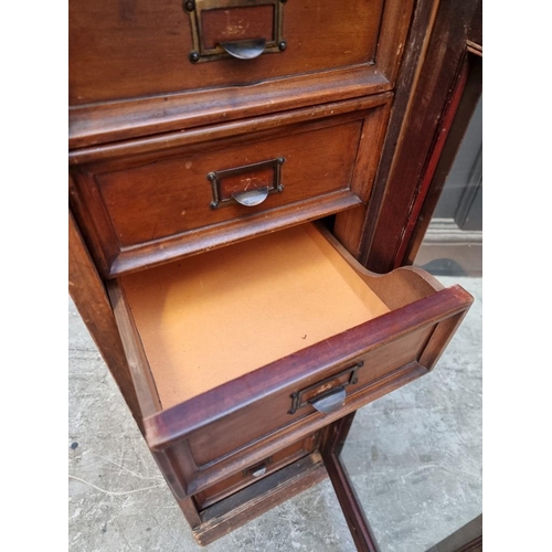1057 - A vintage 'Su-Tall' mahogany haberdasher's chest, with a glazed panelled door enclosing eight small ... 