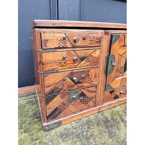1059 - A Japanese parquetry table cabinet, 32cm wide, (formerly metamorphic).