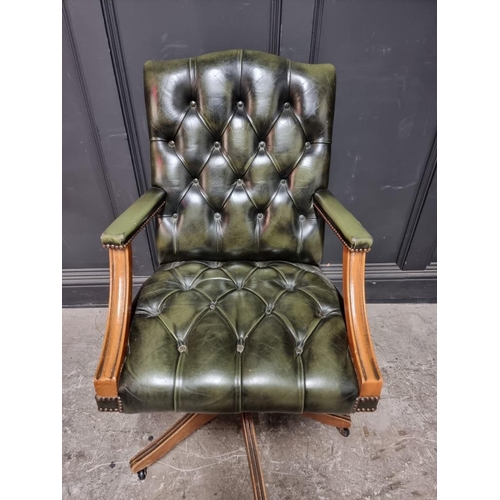 1074 - A buttoned green leather adjustable desk chair. 