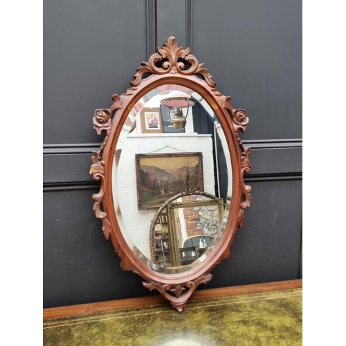 1019 - A carved walnut framed oval wall mirror, 90 x 54.5cm.