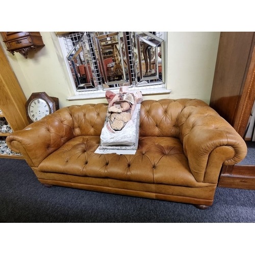 1100A - A Victorian style tan leather Chesterfield settee, with buttoned back and seat, 185cm wide.... 