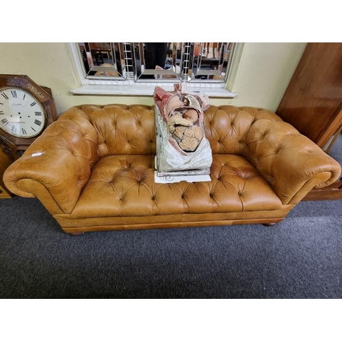 1100A - A Victorian style tan leather Chesterfield settee, with buttoned back and seat, 185cm wide.... 