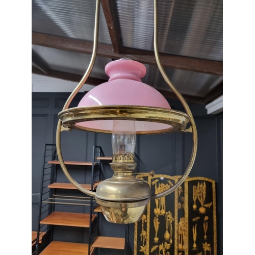 1185 - A brass hanging oil lamp, with pink glass shade, approx 96cm high. 