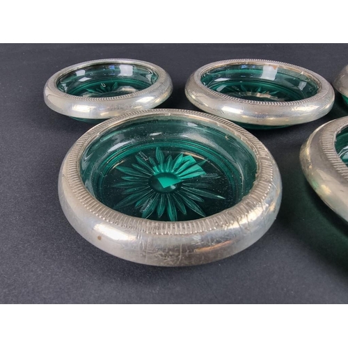 109 - Seven white metal mounted green glass ashtrays, stamped 'Crown Sterling'.