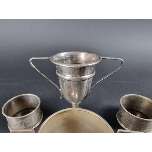 134 - A small group of silver, comprising two small twin handled trophy cups; a pair of silver napkin ring... 