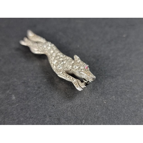 294 - A 1930s fox brooch, with diamond encrusted body and ruby eye, in an unmarked setting, 48mm.... 