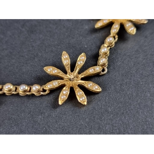 355 - A Victorian or Edwardian yellow metal necklace, decorated five stylised seed pearl flowerheads, (one... 