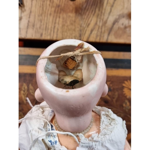 1506 - An antique German bisque head doll, with lace dress and bonnet.