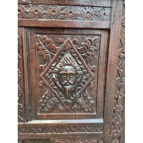 1094 - An interesting late 17th century carved oak panelled coffer, the front incorporating three stylised ... 