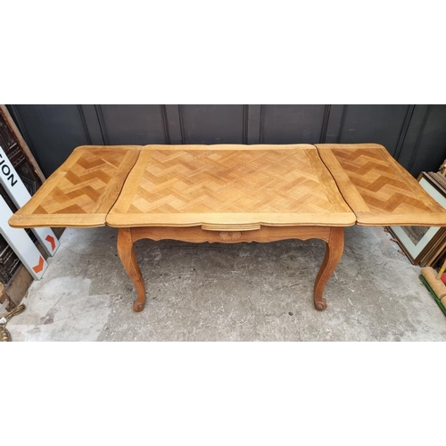 1114 - An oak draw leaf dining table, with parquetry top, 130cm when closed.