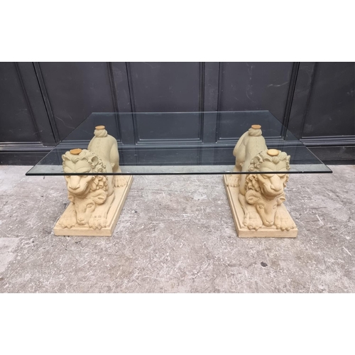 1023 - A composition stone and glass low occasional table, with lion form base, 122cm wide.... 