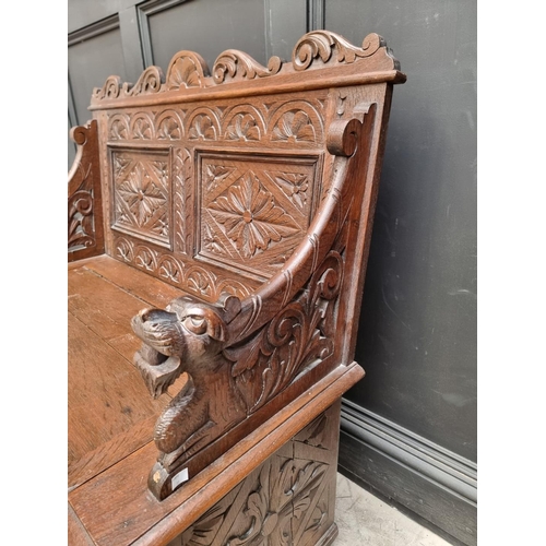 1073 - A circa 1900 carved oak box seat settle, 106cm wide. 