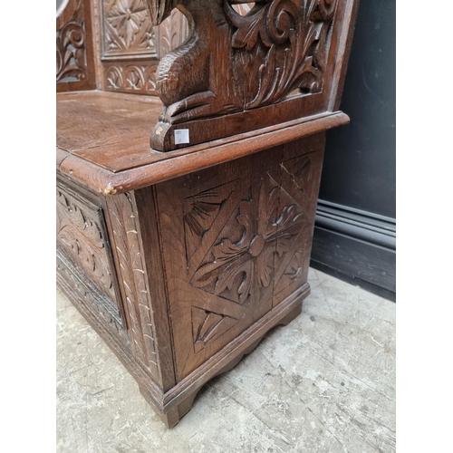 1073 - A circa 1900 carved oak box seat settle, 106cm wide. 