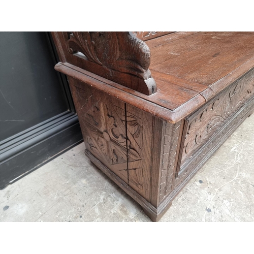 1073 - A circa 1900 carved oak box seat settle, 106cm wide. 