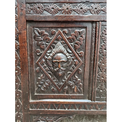 1094 - An interesting late 17th century carved oak panelled coffer, the front incorporating three stylised ... 