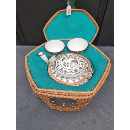 1198 - A Chinese famille rose teapot, cover and two bowls, in wicker case. (4)