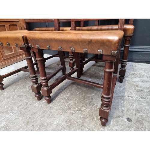 1283 - A set of four late 19th century carved walnut and embossed tanned leather dining chairs, with decora... 