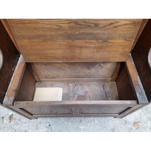 1284 - A reproduction carved oak box seat settle, 86cm wide.